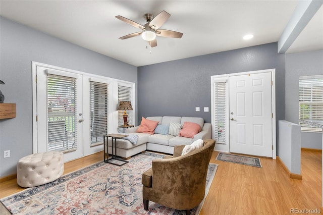living room featuring light wood-type flooring, ceiling fan, and baseboards
