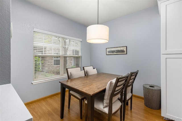 dining room featuring light wood finished floors and baseboards