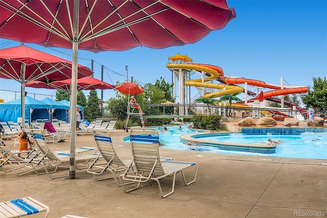 community pool featuring fence and a water slide