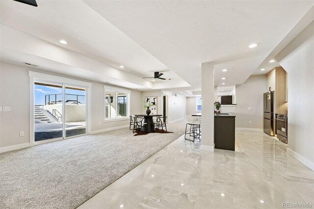 kitchen with ceiling fan, kitchen peninsula, light colored carpet, a kitchen bar, and appliances with stainless steel finishes