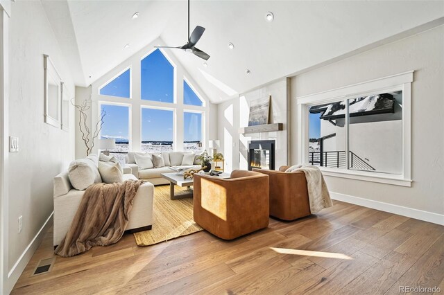 living room featuring ceiling fan, a fireplace, high vaulted ceiling, and hardwood / wood-style flooring