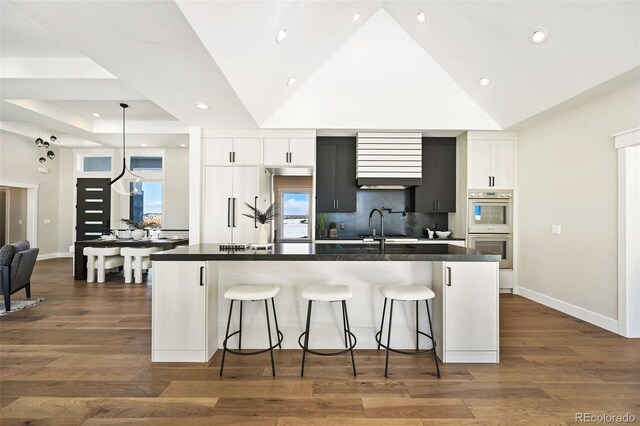 kitchen featuring white cabinets, a spacious island, a breakfast bar area, and double oven