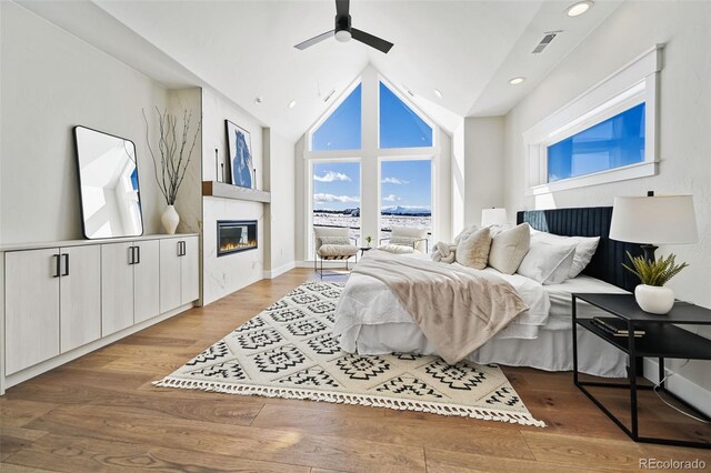 bedroom with wood-type flooring, high vaulted ceiling, and ceiling fan