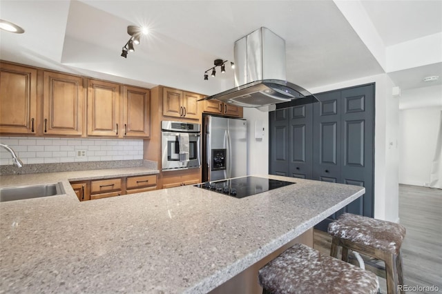 12455 W Alameda Dr, Lakewood, CO 80228 - kitchen with appliances with stainless steel finishes, a sink, island exhaust hood, wood finished floors, and brown cabinets