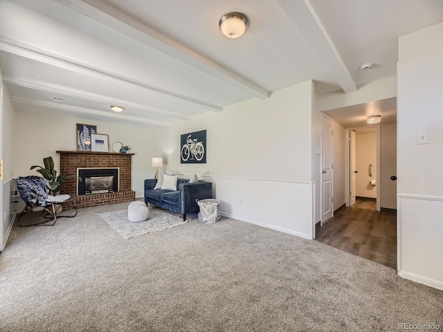 living room with a brick fireplace, beam ceiling, and carpet floors