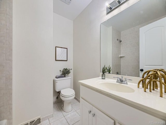 bathroom featuring vanity, toilet, a tile shower, and tile patterned flooring