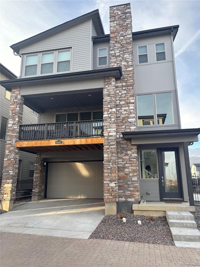 15682 W Girard Ave, Morrison, CO 80465 - contemporary house with a balcony, a chimney, driveway, an attached garage, and stone siding