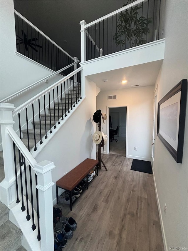 stairway featuring wood-type flooring and a high ceiling