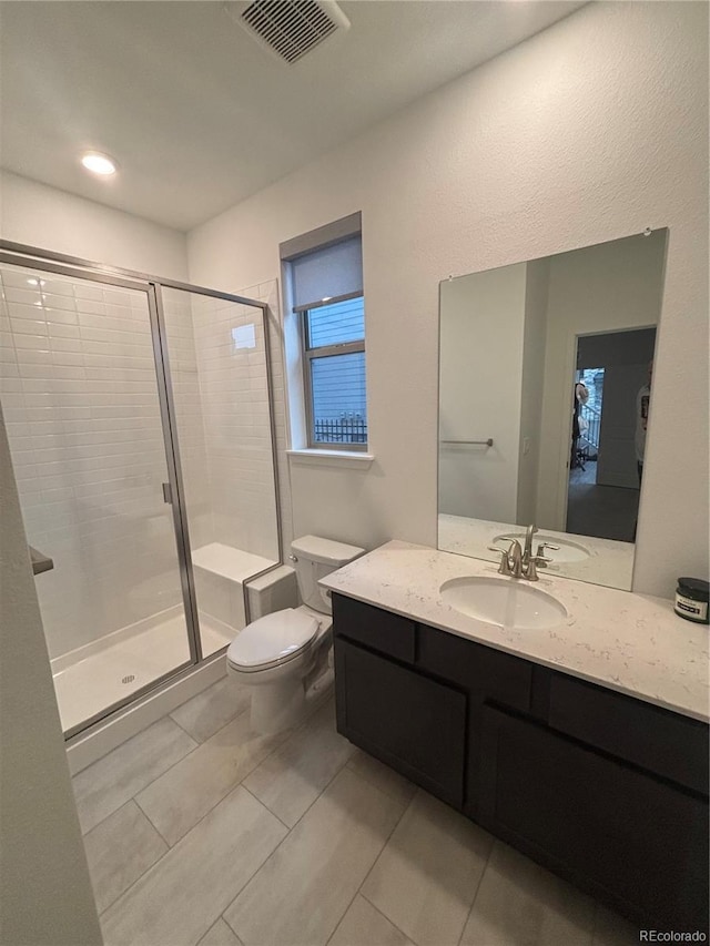 bathroom with tile patterned floors, vanity, a shower with shower door, and toilet