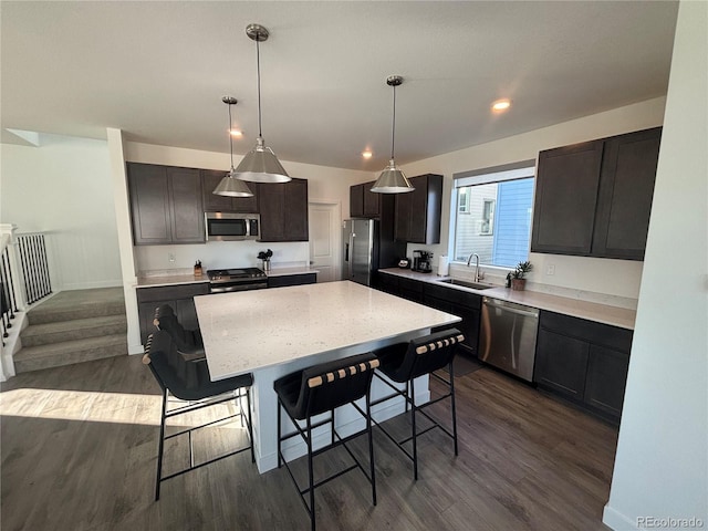 kitchen with a center island, sink, hanging light fixtures, dark hardwood / wood-style floors, and stainless steel appliances