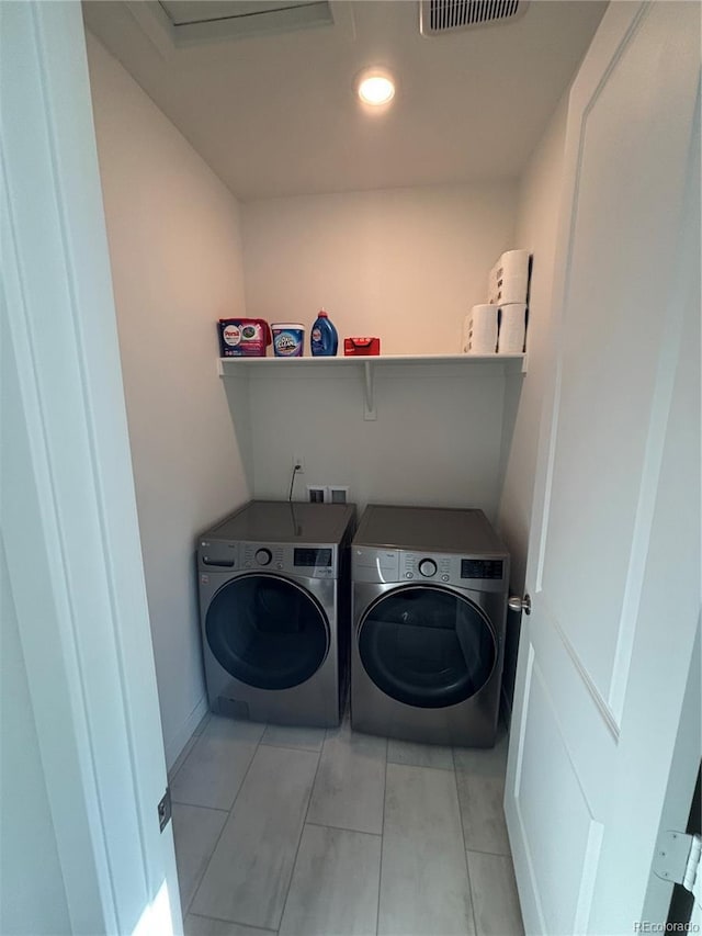 clothes washing area with washer and dryer and light tile patterned floors