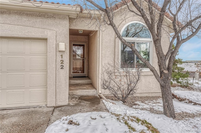 snow covered property entrance with a garage