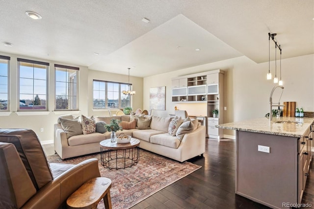 living room with sink, a notable chandelier, dark wood-type flooring, and a textured ceiling