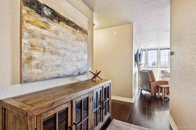 hall featuring dark wood-type flooring and a textured ceiling