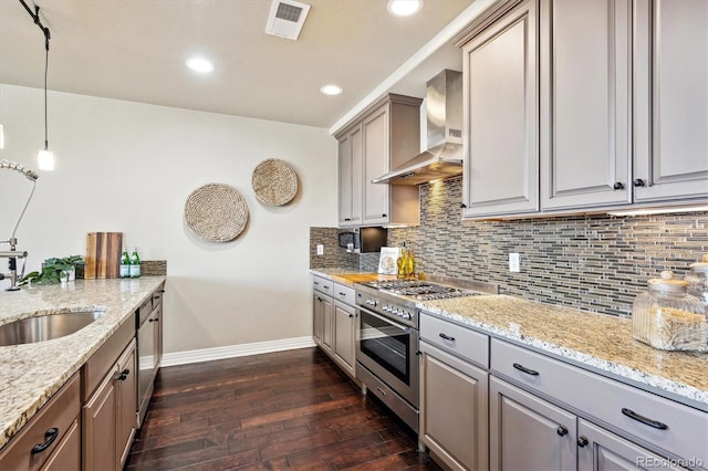 kitchen with dark wood-type flooring, wall chimney exhaust hood, tasteful backsplash, decorative light fixtures, and stainless steel appliances