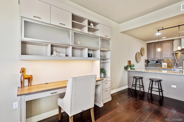 home office featuring sink, dark wood-type flooring, and built in desk