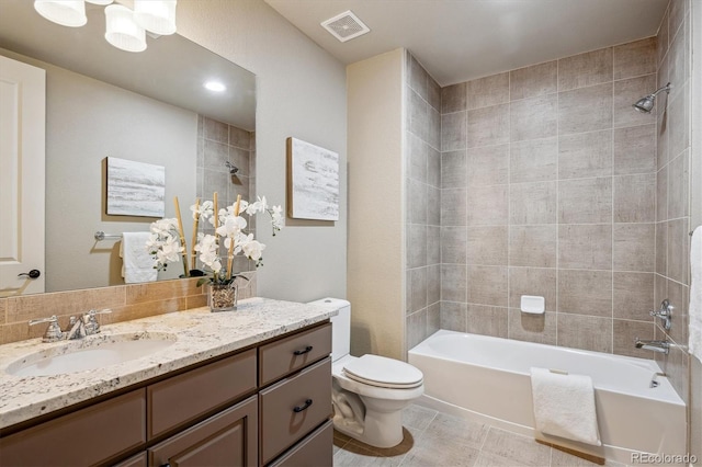 full bathroom with tile patterned floors, vanity, toilet, and tiled shower / bath combo