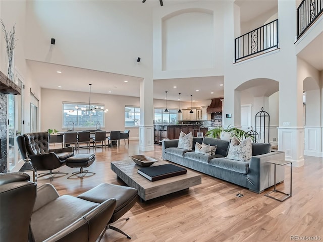 living room with a notable chandelier, a towering ceiling, and light hardwood / wood-style flooring