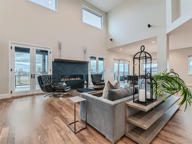 living room featuring a fireplace, a high ceiling, french doors, and a healthy amount of sunlight