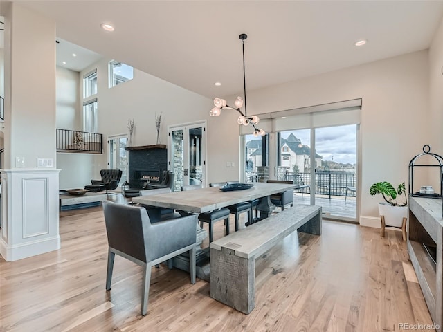 dining space with an inviting chandelier, light hardwood / wood-style floors, and a fireplace