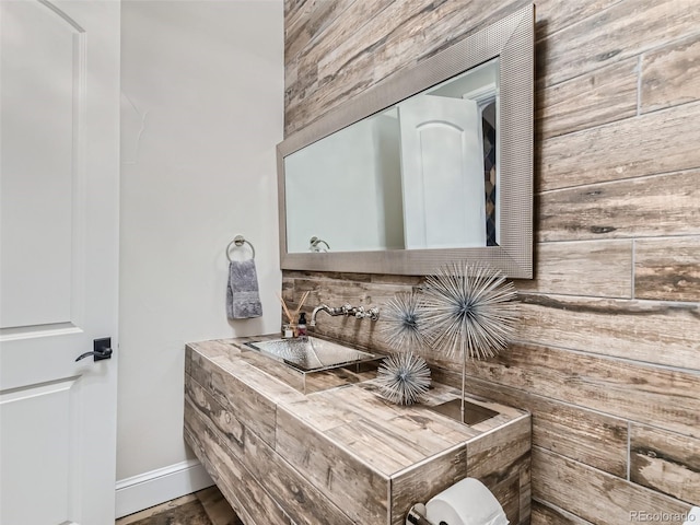 bathroom featuring sink and wood walls