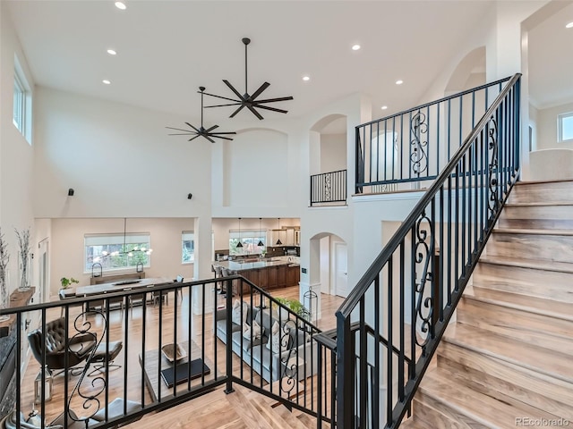 stairway featuring ceiling fan, hardwood / wood-style flooring, and a towering ceiling