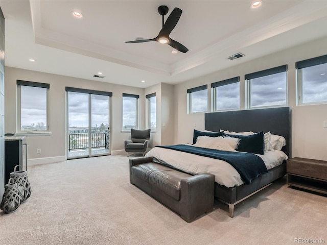 carpeted bedroom with access to exterior, ceiling fan, and a raised ceiling