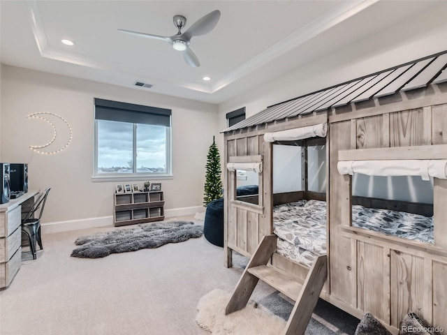 carpeted bedroom with ceiling fan and a raised ceiling