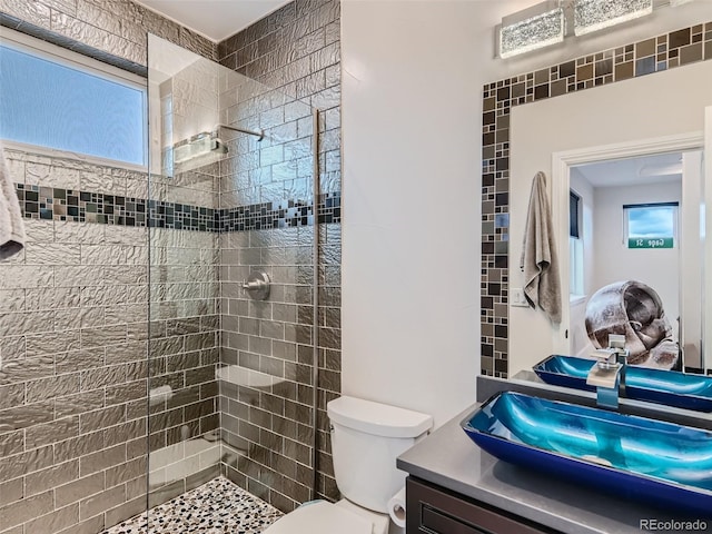 bathroom featuring toilet, vanity, and tiled shower