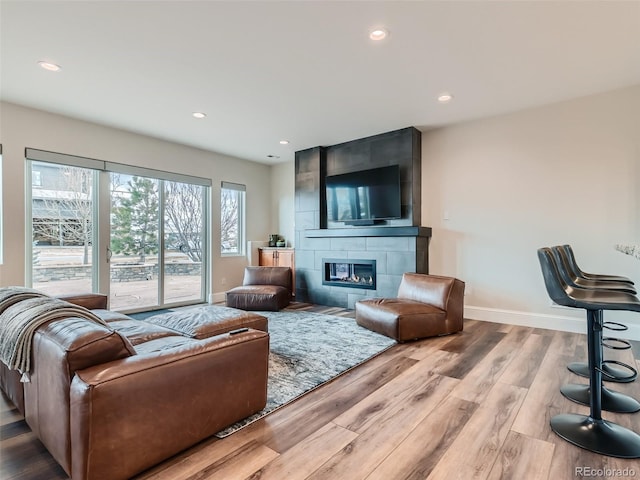 living room featuring light wood-type flooring and a tiled fireplace