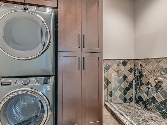 laundry room featuring stacked washing maching and dryer and cabinets