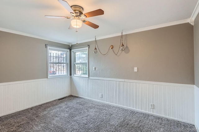 spare room featuring a wainscoted wall, carpet, and crown molding