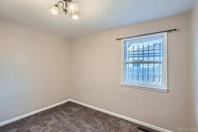 spare room with a chandelier, carpet floors, and baseboards