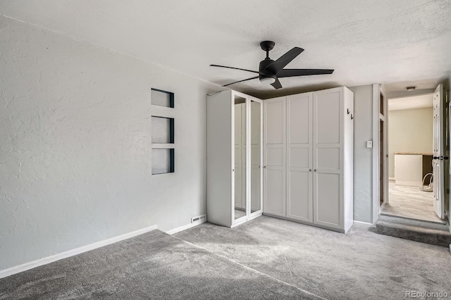 unfurnished bedroom with a textured ceiling, a textured wall, carpet, and baseboards