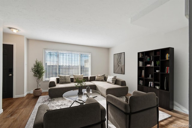 living area with a textured ceiling, wood finished floors, and baseboards