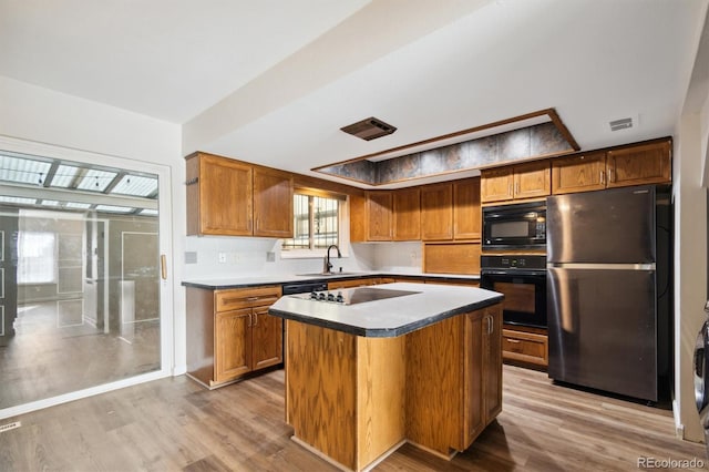 kitchen featuring visible vents, a sink, light wood-style flooring, and black appliances