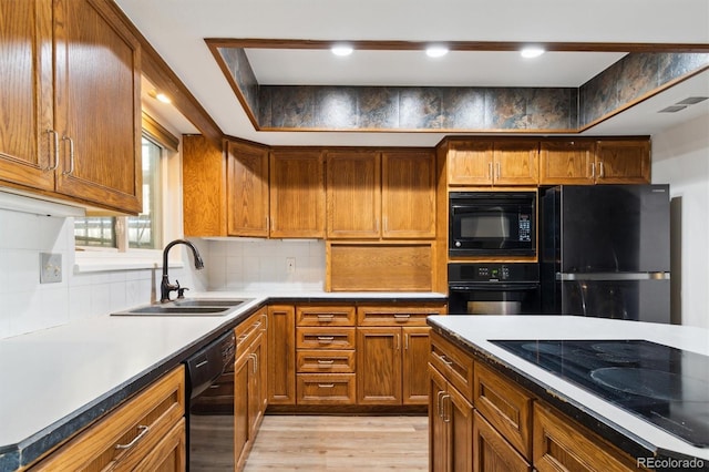 kitchen featuring visible vents, brown cabinets, a sink, black appliances, and backsplash