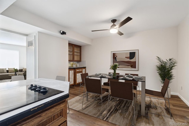 dining area with a ceiling fan, visible vents, dark wood finished floors, and baseboards