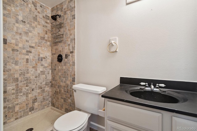 bathroom with vanity, a tile shower, and toilet