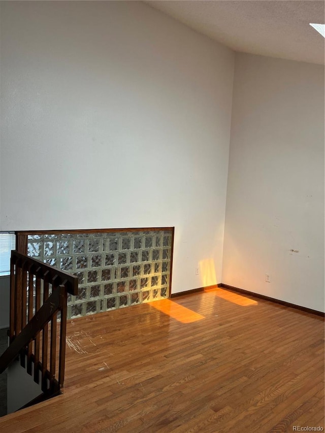 spare room with baseboards and wood finished floors