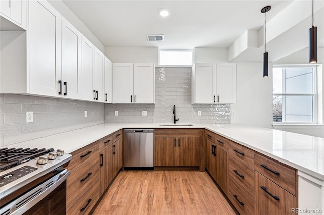 kitchen with sink, white cabinetry, stainless steel appliances, and hanging light fixtures