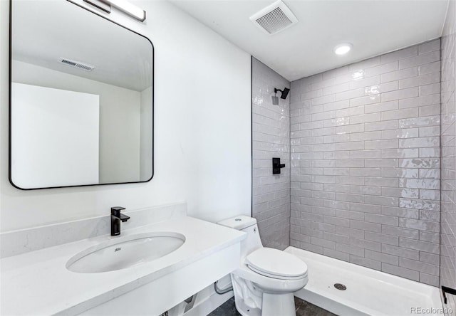 bathroom featuring a tile shower, toilet, and sink