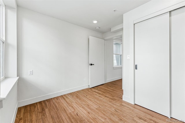 unfurnished bedroom with light wood-type flooring and a closet