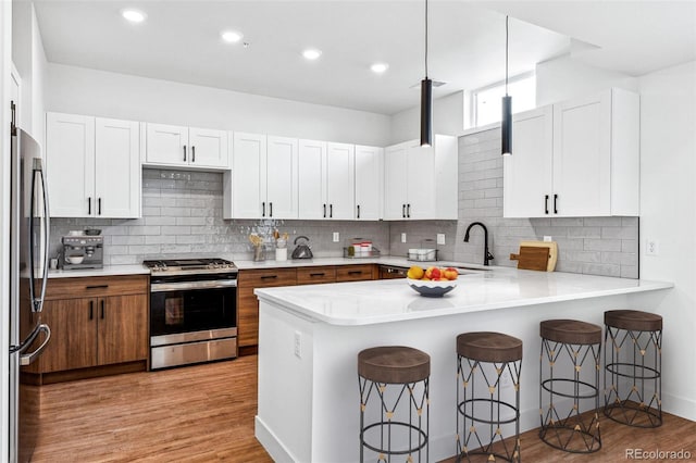 kitchen featuring kitchen peninsula, stainless steel appliances, white cabinetry, and a breakfast bar area