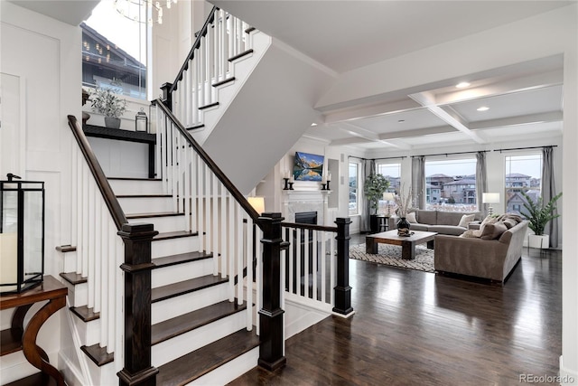 stairs featuring a chandelier, beam ceiling, hardwood / wood-style flooring, and coffered ceiling