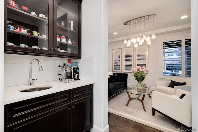 bar featuring pendant lighting, dark wood-type flooring, sink, and tasteful backsplash