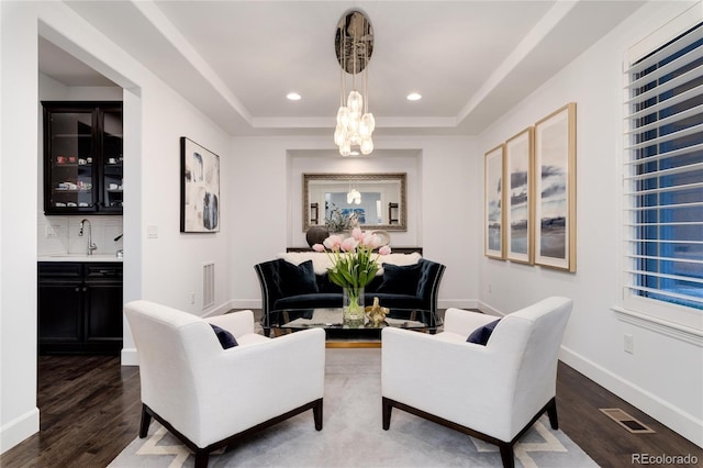 living room featuring a chandelier, dark hardwood / wood-style flooring, a raised ceiling, and sink