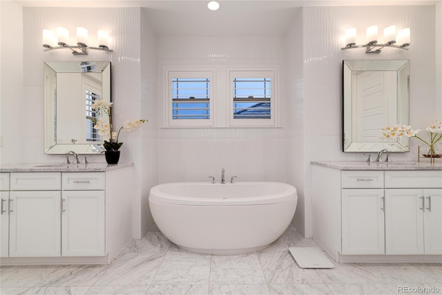 bathroom with vanity, a tub to relax in, and tile walls