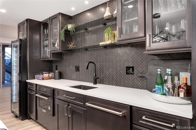 kitchen with light wood-type flooring, dark brown cabinetry, sink, black appliances, and pendant lighting