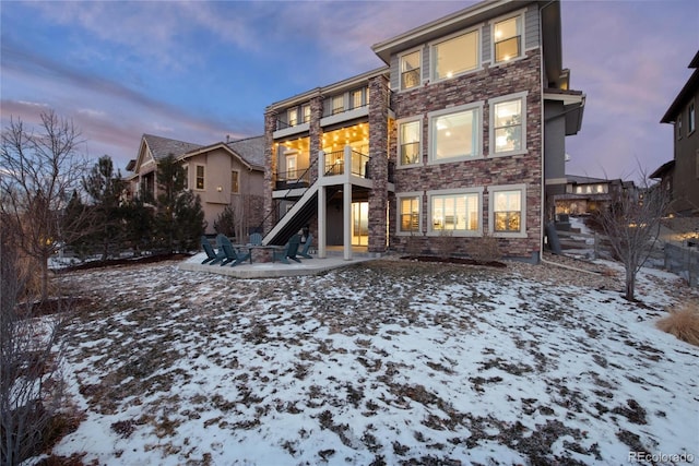 snow covered rear of property with a balcony